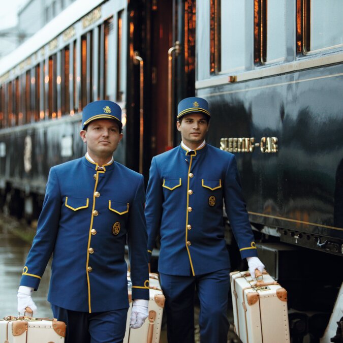 Venice Simplon-Orient-Express at the platform, two stewards in blue uniforms carrying the luggage | © Belmond