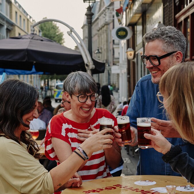 People in Düsseldorf's old town toasting with a beer.  | © Düsseldorf Marketing GmbH, Foto: Sabrina Weniger