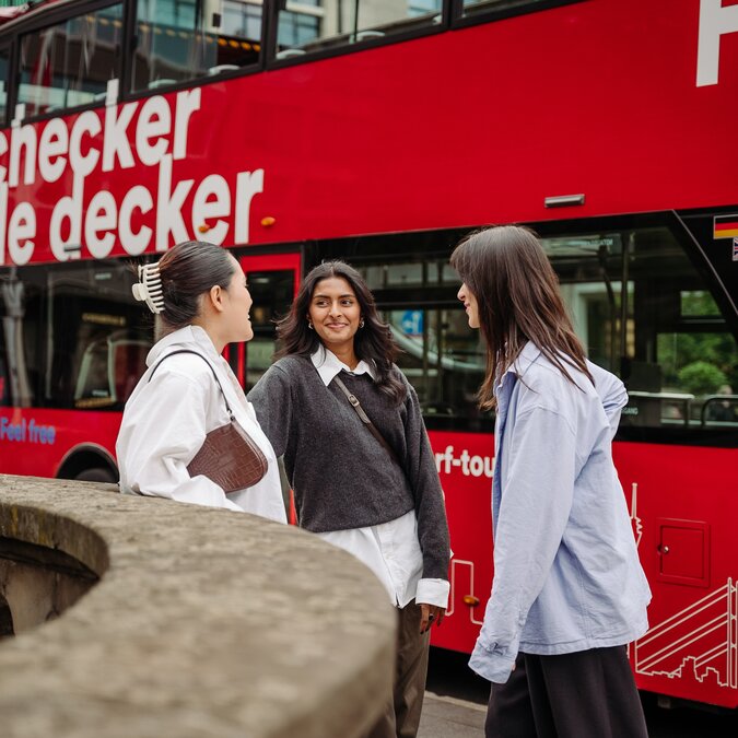 Three young women in front of a hop-on hop-off bus in Düsseldorf. | © Düsseldorf Tourismus - React-EU