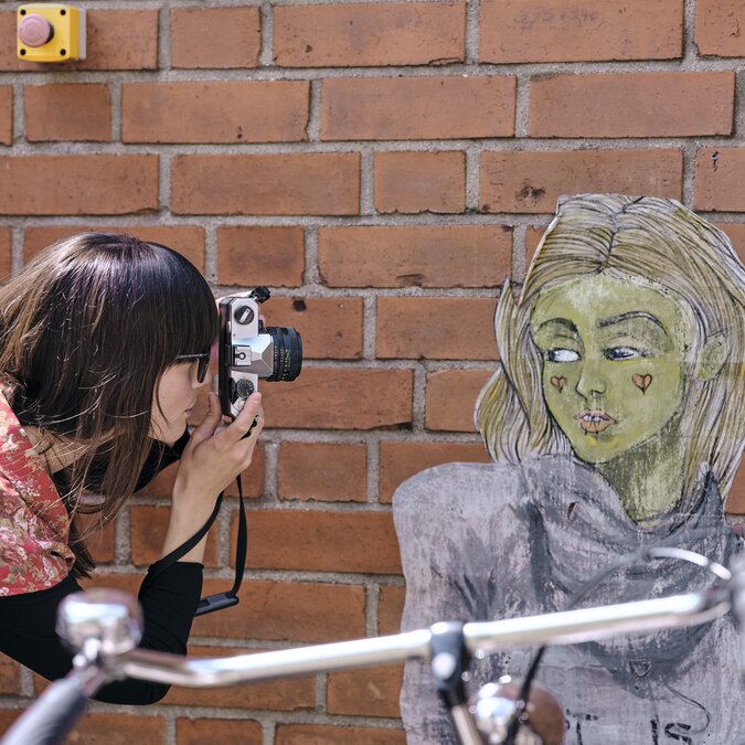 Person taking a photo of a mural, a bicycle in the foreground.  | © Düsseldorf Marketing GmbH, Foto: Markus Luigs