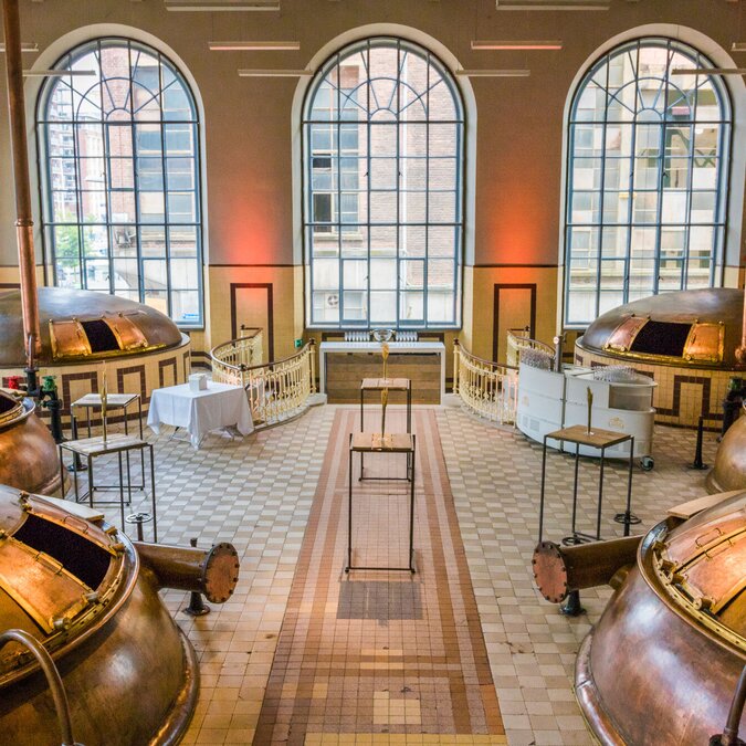 Innenraum einer historischen Brauerei in Leuven mit grossen kupfernen Braukesseln, hohen Rundbogenfenstern und einem hell gefliesten Boden. | © Stad Leuven