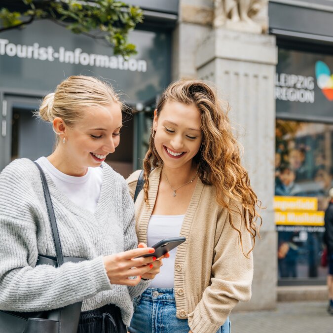 Visitors in front of the Leipzig Tourist Information Center use a smartphone to find their way around the city center. | © Philipp Kirschner | Leipzig Travel