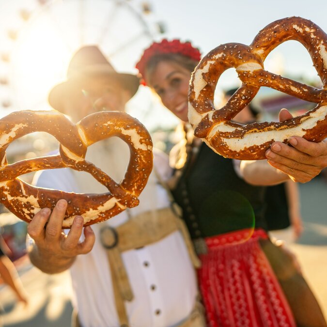 Couple with large pretzels at the Oktoberfest | © shutterstock / 2486289251