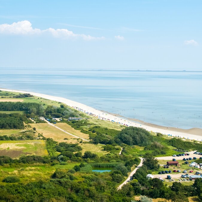 Aerial view of the village of Nieblum on the island of Föhr with green fields, houses and the North Sea coast. | © shutterstock / 2509201019