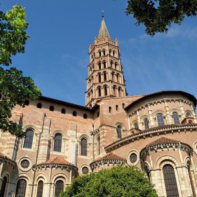 Exterior view of the basilica with a proud tower, numerous windows and framed by trees | © 	 shutterstock / 79360345