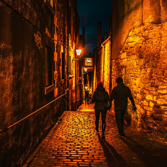 Two people walking through a dark alley | © shutterstock / 1275916531