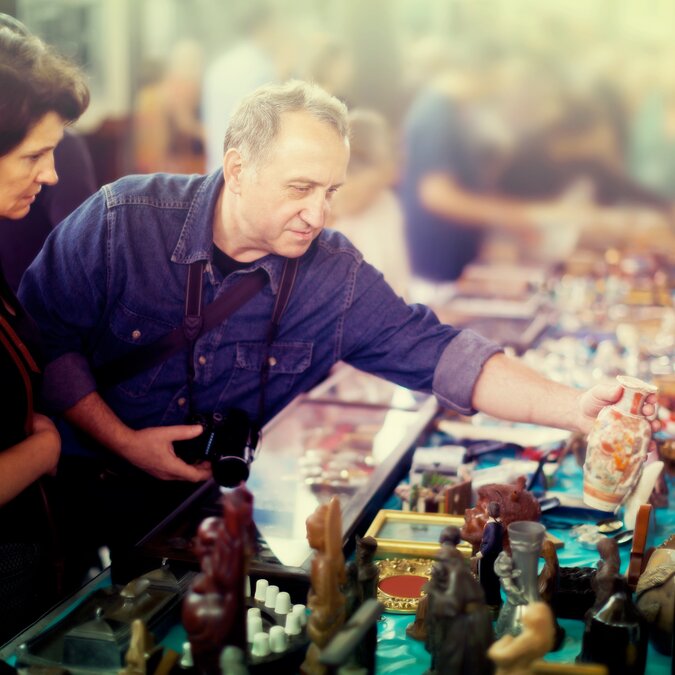 Cheerful couple of tourists study the range of flea market | © Shutterstock 1334550560
