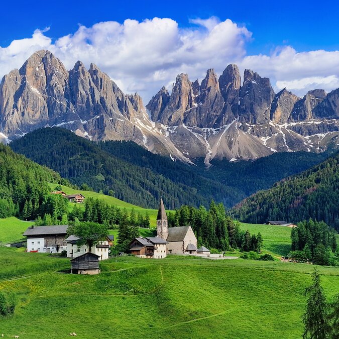 Malerische Bergkulisse der Dolomiten mit einem Dorf im Vordergrund. | © shutterstock / 2454497339