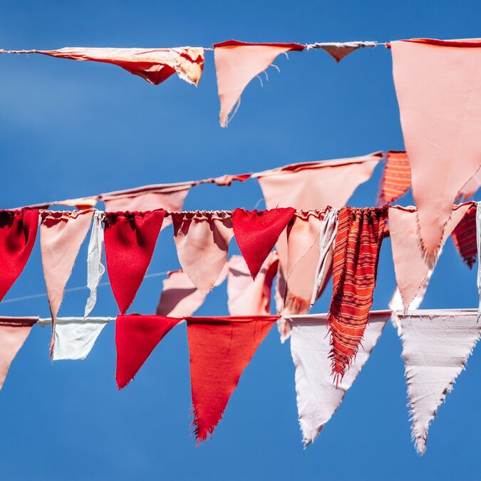 Bunte Wimpel an einer Leine im Wind | © shutterstock / 2602576667